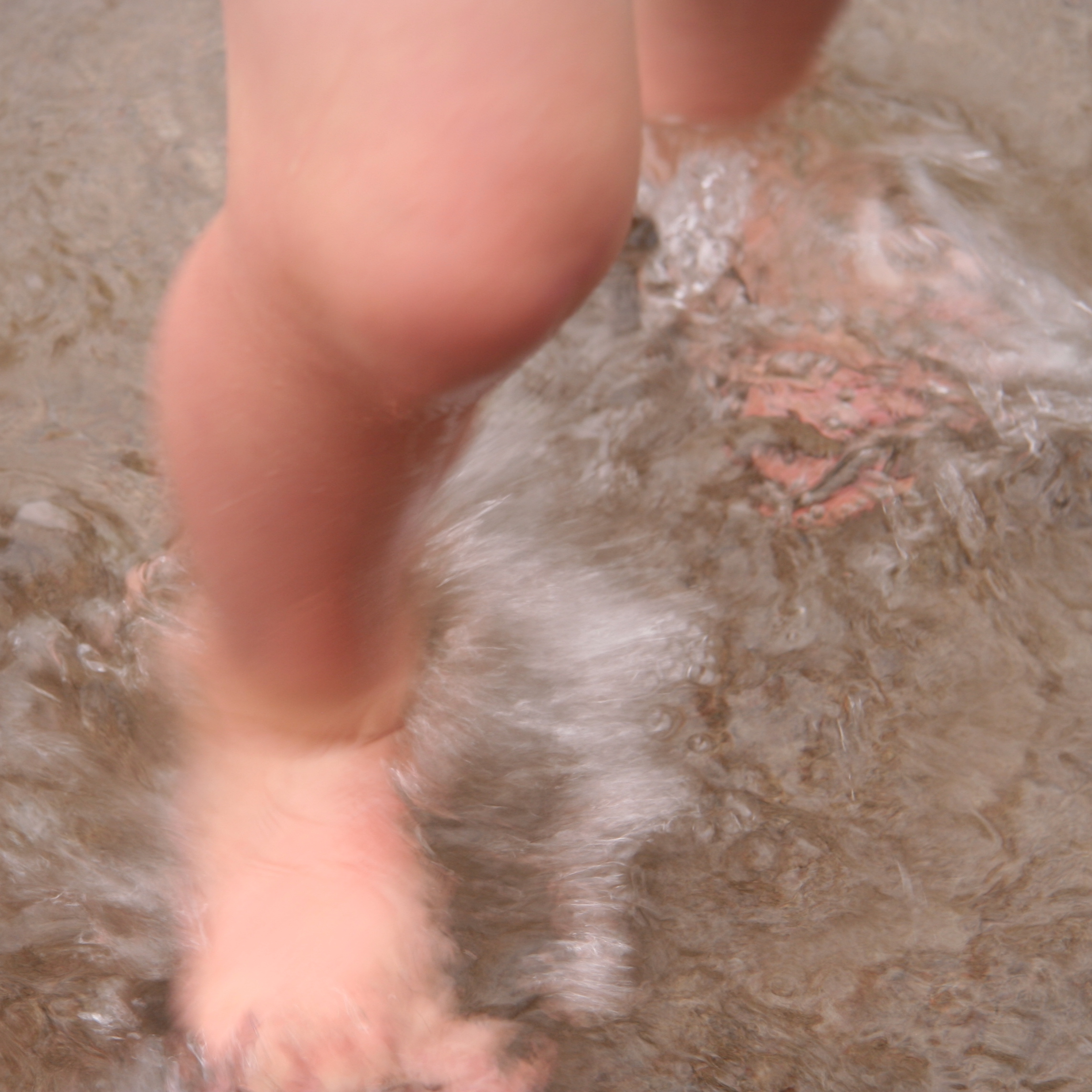 child's legs and bare feet splashing in water