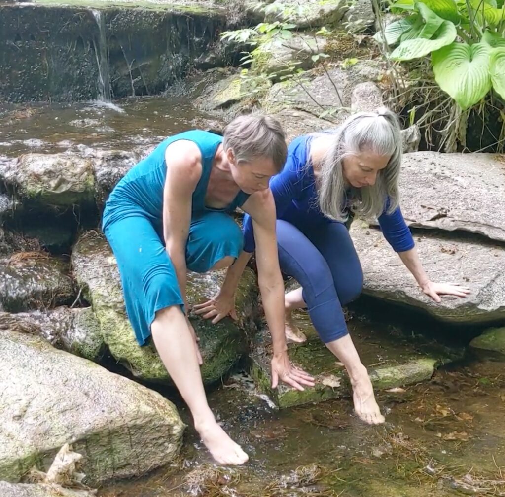 two women moving over rocks in waterfall