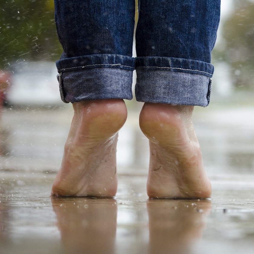 barefoot person standing on wet sidewalk